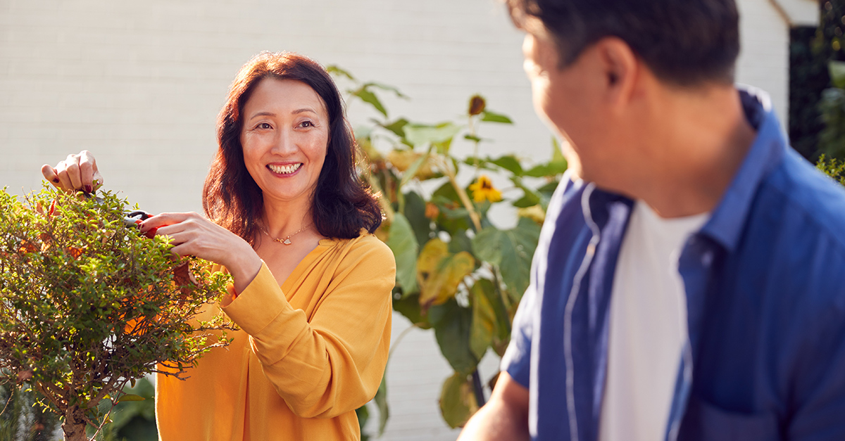 Close up of mature couple watering and pruning plants In garden at home, illustrating the blog topic "Your Passport to Freedom: Navigating Health Insurance as an Early Retiree"