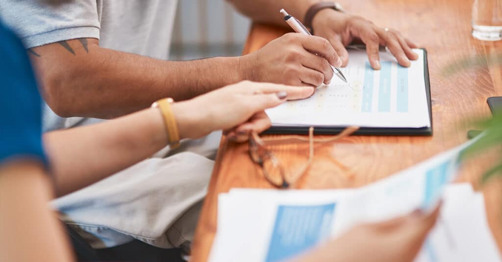 Cropped image of a man and woman's hands filling out paperwork at a table