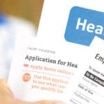 Open enrollment healthcare benefits forms with a medical doctor in the background.